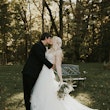 Bride Kissing Groom Wearing Bridal Gown Called Raelynn by Rebecca Ingram