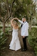 Groom Dancing With Bride In A White Strapless Wedding Dress With Bow On The Back Named Mitchell By Maggie Sottero