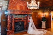 Real Bride In Front Of Stone Fireplace Wearing A Fitted White Wedding Dress Named Veronique by Maggie Sottero