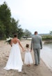 Bride Wearing Simple Chiffon Wedding Dress Called Marta Lynette By Rebecca Ingram Walking Away With Flower Girl And Groom Near Water