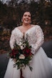 Plus Size Bride In Lace Long Sleeve Wedding Dress Called Mallory Dawn By Maggie Sottero Holding Red Bouquet