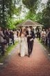 Bride wearing Fiona by Maggie Sottero walking with her husband from their ceremony