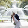 Bride and groom kissing by huge fountain.