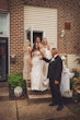 Bride wearing Fiona by Maggie Sottero walking out of her house with her bridal party