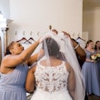 Bridesmaids putting the veil on the bride wearing wedding dress called Veda.