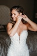 Bride Wearing Lace Mermaid Wedding Gown Called Montgomery By Sottero and Midgley Putting on Earrings