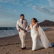 Bride wearing Johanna Lane by Maggie Sottero walking on the beach with her husband