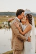 Bride Wearing Keyhole Back Halter Wedding Dress Called Bellarose By Rebecca Ingram About To Kiss Groom