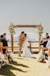 Bride Wearing Keyhole Back Halter Wedding Dress Called Bellarose By Rebecca Ingram Kissing Groom At The Alter