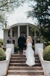 Groom Walking Up Stairs with Bride in Glittery Mermaid Wedding Gown with Illusion Lace Back by Maggie Sottero