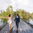 Bride Wearing Grecian Inspired Wedding Dress Called Gabrielle By Maggie Sottero Walking On A Boardwalk With Groom