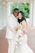 Newlyweds wearing ivory attire standing close.