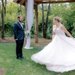 Bride twirling her skirt of wedding dress called Pierce as groom watches lovingly.