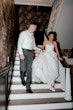 Bride wearing Anniston by Maggie Sottero walking down the stairs with her husband