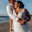 Bride wearing Johanna Lane by Maggie Sottero being held by her husband on the beach