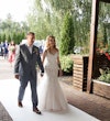 Bride Wearing Fit-and-Flare Wedding Dress Called Wendi By Rebecca Ingram Walking With Groom