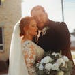Bride Wearing Lace Long-Sleeve Wedding Gown Called Raphael By Maggie Sottero Holding Groom