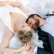 Bride and groom lying on the bride's dress.