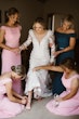 Bridal Party Helping Bride Get Ready. Bride in Vintage Inspired Puff Sleeve Mermaid Wedding Dress in 3-D Floral Motifs Called Cruz by Sottero & Midgley