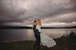 Groom lifting his bride near a lake.