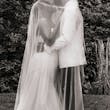 Bride Wearing Simple Fit and Flare Wedding Dress Called Anniston Lane Kissing Groom Underneath Her Veil