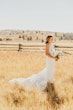 Bride Wearing Keyhole Back Halter Wedding Dress Called Bellarose By Rebecca Ingram In A Field