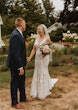 Bride wearing Greenley wedding dress by Maggie Sottero holding hands with her husband