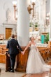 Bride wearing Marvine wedding gown by Sottero and Midgley while holding hands with her husband