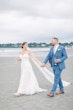 Bride Wearing Boho Sheath Wedding Dress Called Marisol By Rebecca Ingram Walking On The Beach With Groom