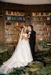 Bride wearing Zinaida by Maggie Sottero kissing her husband in a library