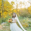Bride Wearing Satin Aline Wedding Dress Called Ekaterina By Maggie Sottero In A Forest Holding A Bouquet