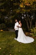 Bride Wearing Simple Fit and Flare Wedding Dress Called Anniston Lane Holding Groom In A Green Garden