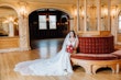 Real Bride Wearing A Fitted White Wedding Dress Named Veronique by Maggie Sottero Holding Red Roses