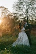 Bride Wearing Floral Ballgown Wedding Dress Called Derrick Marie With Groom In A Field