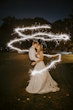 Bride Wearing Sparkly Ballgown Wedding Dress Called Shasta By Sottero And Midgley Kissing Groom With Sparklers Surrounding Them