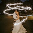 Bride Wearing Sparkly Ballgown Wedding Dress Called Shasta By Sottero And Midgley Kissing Groom With Sparklers Surrounding Them