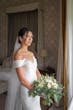 Bride Wearing Simple Off-the-shoulder Wedding Dress Called Josie By Rebecca Ingram Holding White Rose Bouquet