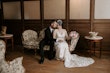 Bride Wearing Rustic Lace Wedding Dress Called Larkin Lynette By Rebecca Ingram With Groom Sitting On A Couch