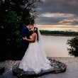 Bride and groom by lake at sunset.