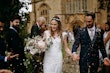 Confetti throw with bride holding mixed pastel colored bouquet holding grooms hand.