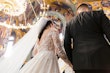 Bride wearing Zander by Sottero and Midgley holding hands with her husband