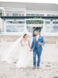 Bride Wearing Boho Sheath Wedding Dress Called Marisol By Rebecca Ingram Holding Hands With Groom On The Beach