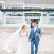 Bride Wearing Boho Sheath Wedding Dress Called Marisol By Rebecca Ingram Holding Hands With Groom On The Beach