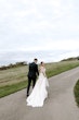 Bride Wearing Lace Backless Wedding Dress Called Chauncey By Sottero And Midgley Walking On A Path With Groom