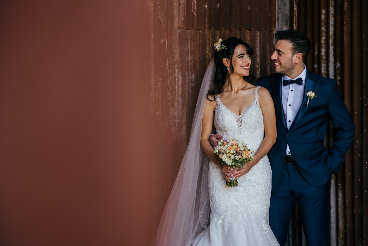 Bride With Groom Outside a Barn Wearing Wedding Gown Called Giana Lynette by Maggie Sottero