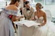 Bride wearing Indiana by Maggie Sottero and her husbandn signing their marriage license