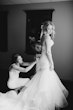 Bridesmaids fastening the bride's dress at the back.
