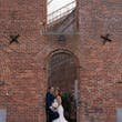 Bride Wearing Lace Crepe Bridal Dress Called Bracken By Sottero And Midgley With Groom Under A Brick Archway