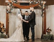 Bride Wearing Lacey Sheath Long Sleeve Wedding Dress Called Francesca By Maggie Sottero Holding Hands With Groom During Ceremony