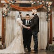 Bride Wearing Lacey Sheath Long Sleeve Wedding Dress Called Francesca By Maggie Sottero Holding Hands With Groom During Ceremony